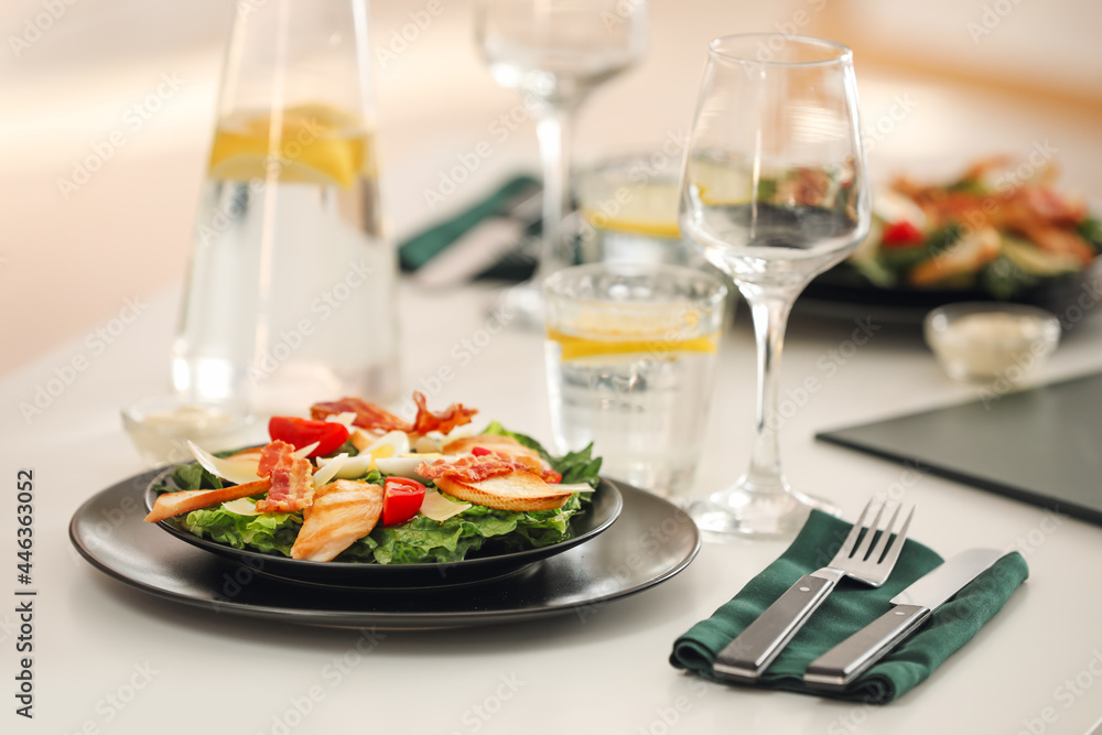 Plate with tasty Caesar salad on table in restaurant