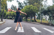 © FABIAN PONCE GARCIA - Latin teenage dancer girl with black dress walking elegantly with ballet shoes on a pedestrian crossing in the street