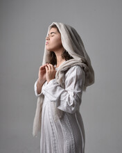 Close Up  Portrait Of Young Woman Wearing Classical White Gown And A Head Covering Veil In Biblical Style, Standing Worshiping  Pose On Light Studio Background.