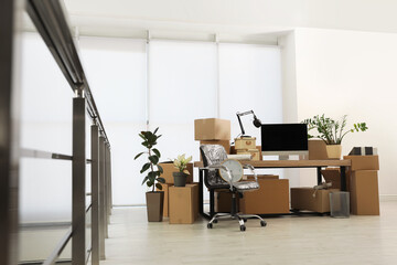 Cardboard boxes, computer and furniture in new office. Moving day