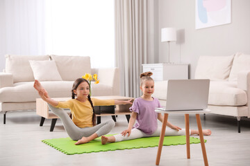 Wall Mural - Cute little girls warming up before online dance class at home