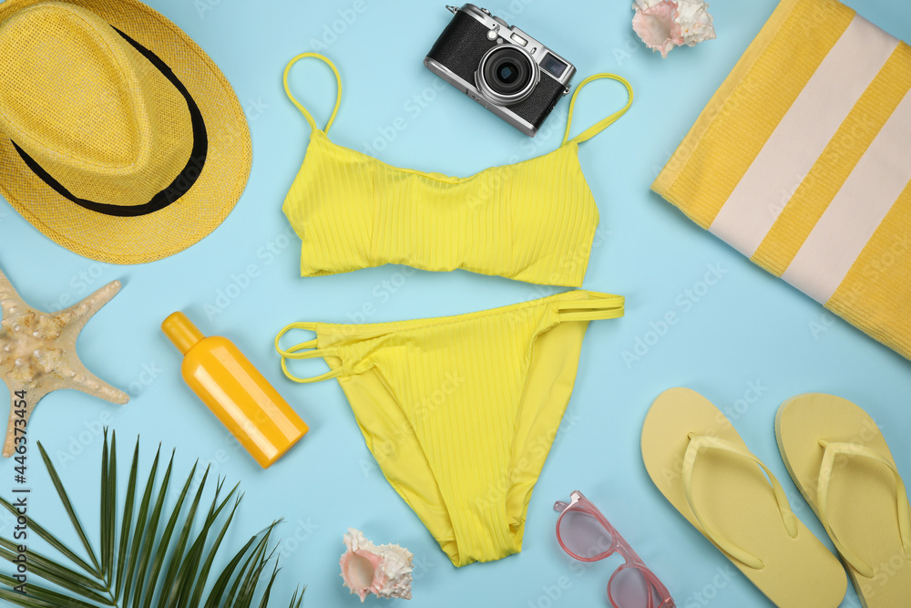 Flat lay composition with swimsuit and beach accessories on light blue background - obrazy, fototapety, plakaty 