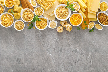 Poster - Pasta. Various kinds of uncooked pasta and noodles over stone background, top view with copy space for text. Italian food culinary concept. Collection of different raw pasta on cooking table