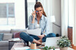© nenetus - Business woman doing video call with laptop while sitting on the table in living room at home.