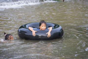 a kids play and lying on a tire floating in water Filmed in Chiang mai, Thailand.