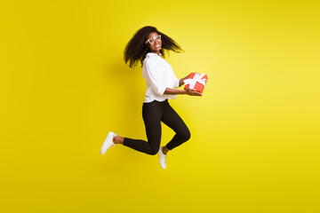 Wall Mural - Full length body size photo woman jumping high keeping present box smiling isolated vivid yellow color background