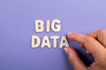 Wall Mural - big data. white wooden letters with text and a woman's hand on a purple background