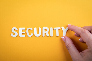 Wall Mural - SECURITY. White wooden letters with text and a woman's hand on a yellow background