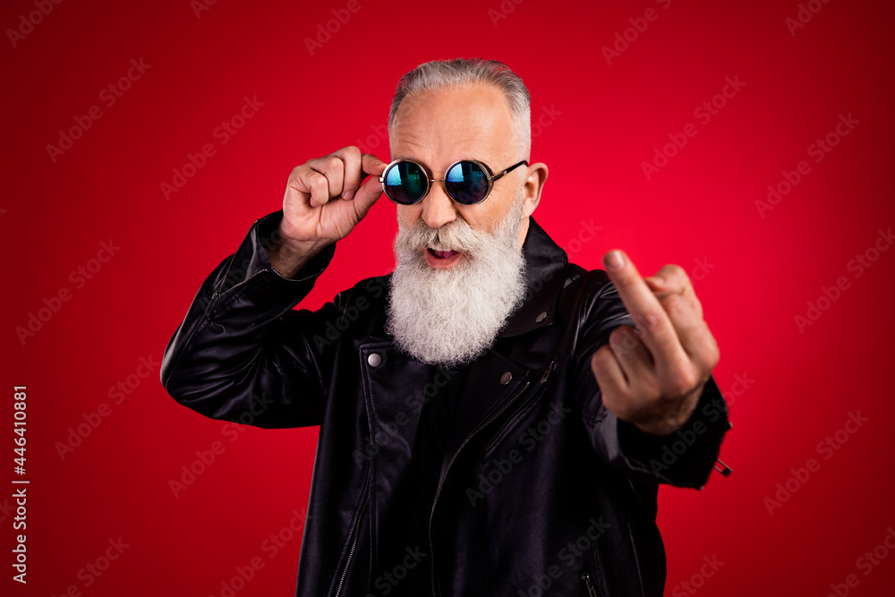 Portrait of attractive fashionable elderly grey-haired man showing middle finger touching specs isolated over bright red color background - obrazy, fototapety, plakaty 