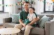 © Syda Productions - family, fatherhood and people concept - portrait of happy smiling father and little son sitting on sofa at home party