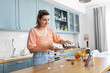 © Syda Productions - culinary and people concept - happy smiling young woman with tablet pc computer making cocktail drinks at home kitchen