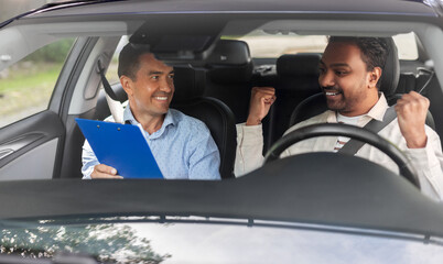 Wall Mural - driver courses, exam and people concept - happy smiling indian man and driving school instructor with clipboard in car