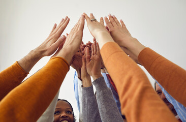 Wall Mural - Close up shot of diverse group of happy positive friendly people raising arms up in the air and joining hands. Concept of business team, teamwork, cooperation, strong community, and support