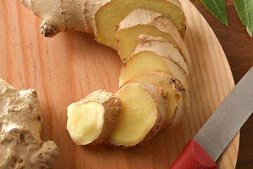 Wall Mural - Ginger root sliced on wooden cutting board close up