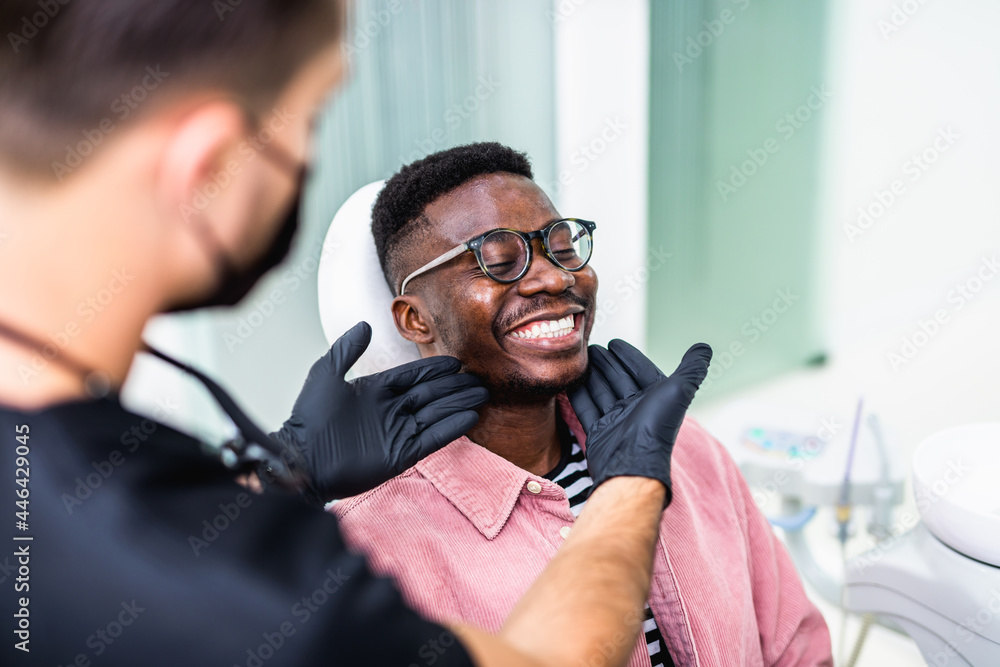 African American young man having a visit at the dentist's. He is sitting on chair at dentist office in dental clinic. - obrazy, fototapety, plakaty 
