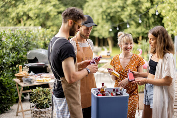 Friends with fridge full of alcohol at party outdoors, young people gathering for a picnic, carrying alcohol drinks at backyard