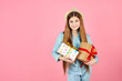 © wertinio - Smiling girl in jeans clothes and straw hat isolated on pink background. Valentine's Day, Women's Day, birthday concept. Hold present box with gift ribbon bow.