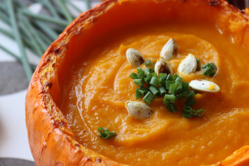 Pumpkin soup on a table. Delicious autumn soup made of carrots, sweet potato and butternut squash. Comfort food concept. Butternut squash soup close up photo. Creamy soup texture. 

