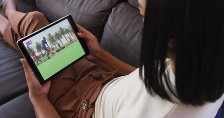 Canvas Print - Composite of woman sitting at home on couch watching hockey match on tablet