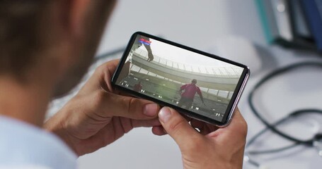 Wall Mural - Composite of male doctor watching rugby match on smartphone