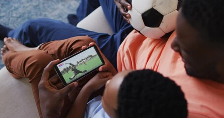 Wall Mural - Composite of father and son at home watching hockey match on smartphone