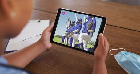 Poster - Composite of woman sitting at table with face mask, watching baseball during covid 19 on tablet