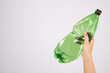 Close-up of female hand holding green plastic bottle on white background.