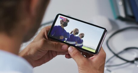 Wall Mural - Composite of male doctor watching baseball game during covid 19 on smartphone