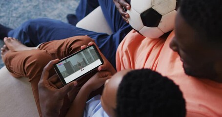 Poster - Composite of father and son at home watching athletics running event on smartphone