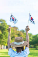 Wall Mural - Woman hand holding Korea flag on nature background. National Foundation, Gaecheonjeol, public Nation holiday, National Liberation Day of Korea and happy celebration concepts