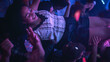 © Gorodenkoff - Music Festival Goers Party with Their Hands Up in the Air at a Concert in a Night Club. Fans Hold a Girl Up in the Air and Cheering for the Band. Bright Colorful Strobing Lights Makes the Atmosphere.