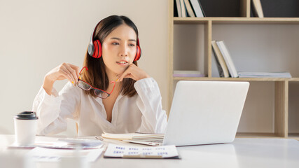 Asian businesswoman working with laptop and calculator with graphing documents to analyze and calculate company finances in office