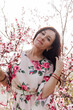© dmitriisimakov - beautiful woman in a dress in the garden of flowering trees in the spring