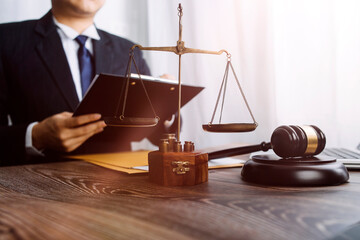 Justice and law concept.Male judge in a courtroom with the gavel, working with, computer and docking keyboard, eyeglasses, on table in morning light