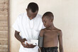 African male nurse measuring blood pressure to an African village kid with the help of a sphygmomanometer.