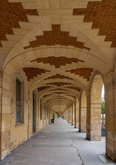 Paris, France - 07 16 2021: Le Marais district. View of arcades of Place des Vosges