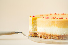 Cheesecake Cut With Yellow Mango Mash Layer On The Beige Background