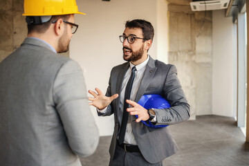 Wall Mural - Supervisor talking to a architect and suggest innovations about building. Construction site interior.