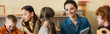 © LIGHTFIELD STUDIOS - happy young teacher smiling near interracial kids in montessori school, banner