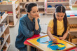 © LIGHTFIELD STUDIOS - young teacher looking at asian child combining earth map puzzle in montessori school