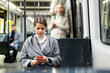 © JackF - Positive woman reading from mobile phone screen in tram. High quality photo