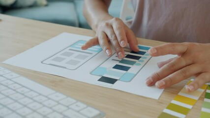 Close-up of smartphone application developer using device screen picture and color palette working at desk indoors. Technology and gadgets concept.