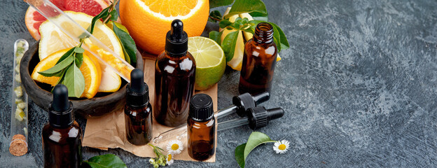 Sticker - Bottles of essential aroma oils with citrus on dark gray background.