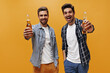 © Look! - Excited young men in white trendy t-shirts and checkered shirts rejoice and hold beer bottles on orange isolated background.