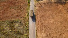 Aerial Hovering Footage Of A Truck Loaded With Sugarcane During The Afternoon Passing Though Tilled Farmlands On A Narrow Asphalt Road In  Thailand.