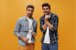 © Look! - Young charming friends feel awkward and pose on orange background. Emotional guys in checkered shirts look into camera.