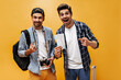© Look! - Emotional excited men in stylish checkered shirts rejoice and smile on orange background. Travelers hold tickets and retro camera.