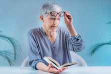 Senior Woman With Eyeglasses Having Problems With Book Reading. Indication For Cataract, Glaucoma, And Vision Loss In The Elderly.