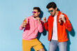 © Look! - Young cool stylish friends dance and have fun on blue background. Man in pink hoodie and guy in orange jacket hold beer bottles.