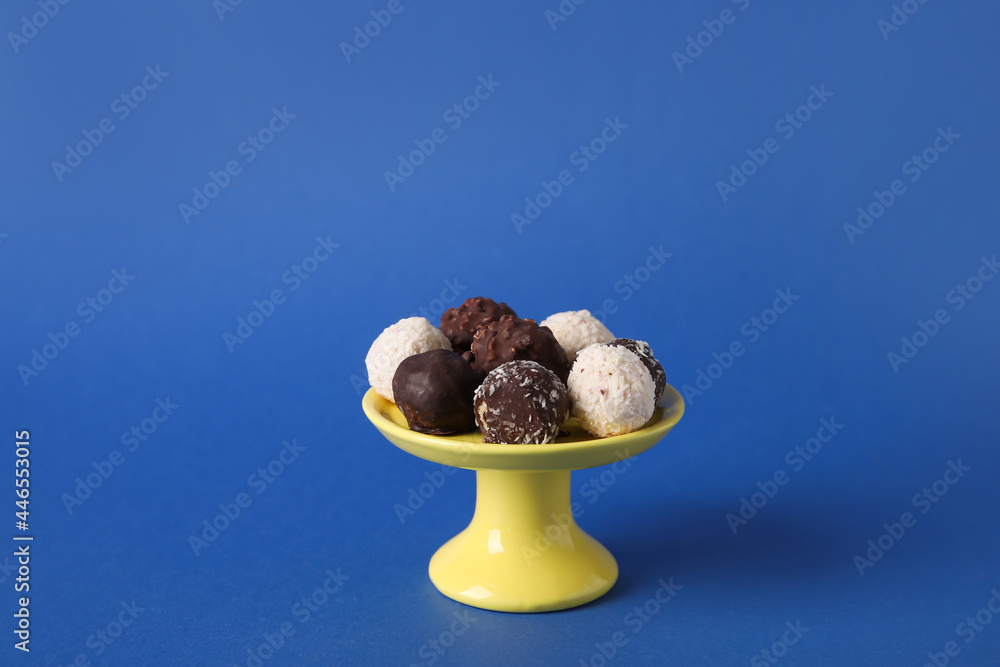 Dessert stand with sweet chocolate candies on color background